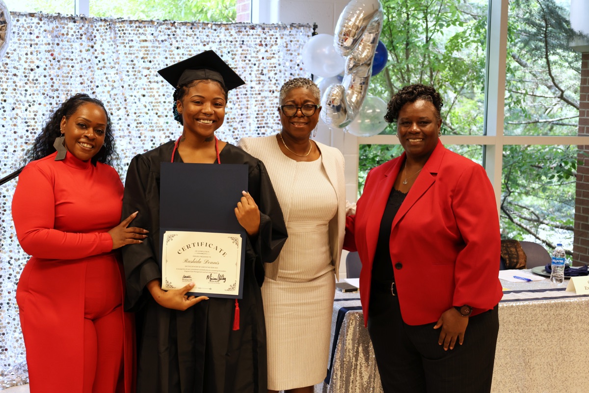 Ladders graduate receiving certificate with program staff